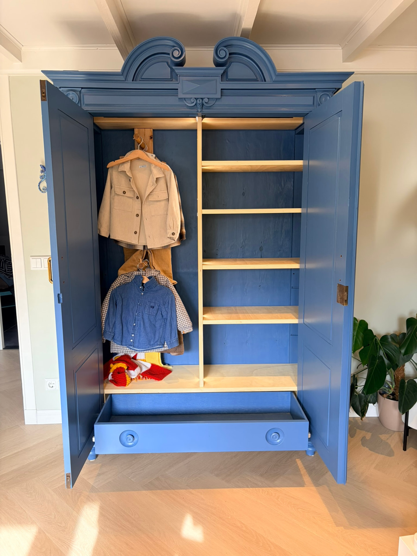 De kast met open deuren: hanggedeelte, legplanken en een lade
