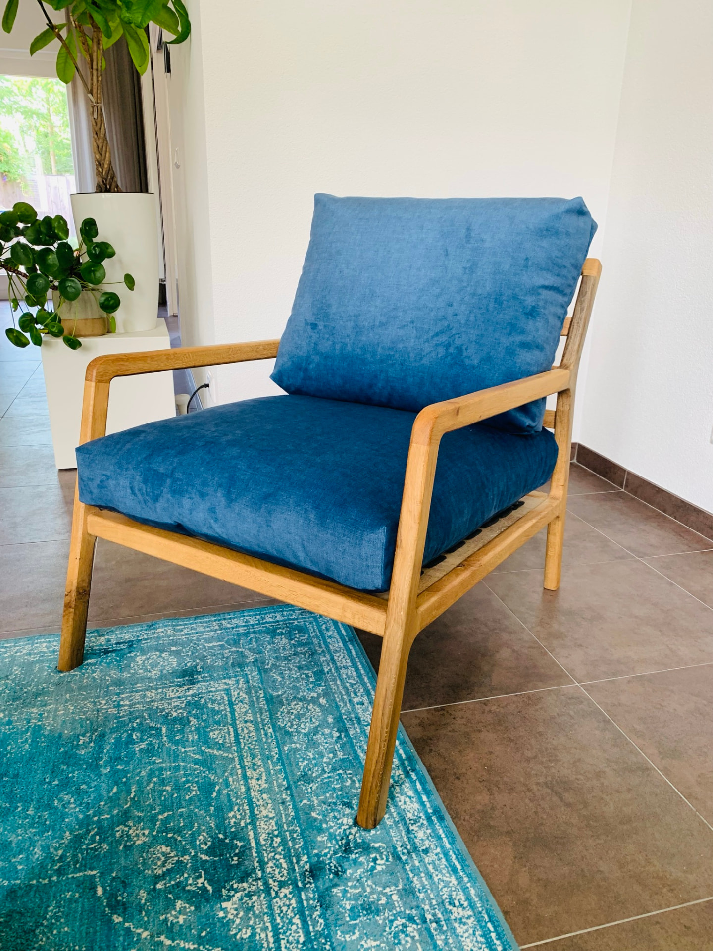 De eiken loungefauteuil met blauwe zit- en rugkussens in de woonkamer