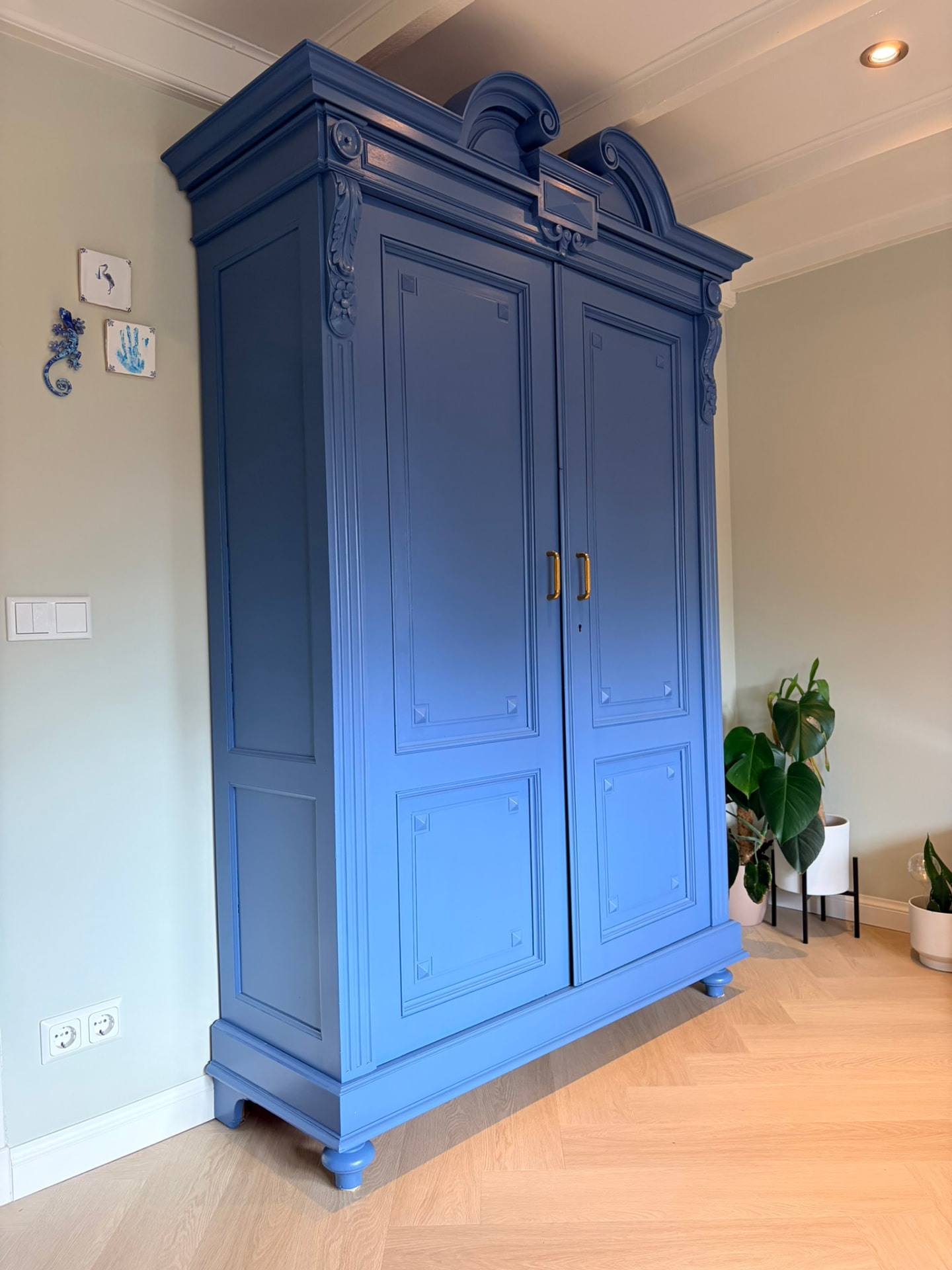 De gerestaureerde kast in blauw, met het originele snijwerk en nieuwe grepen