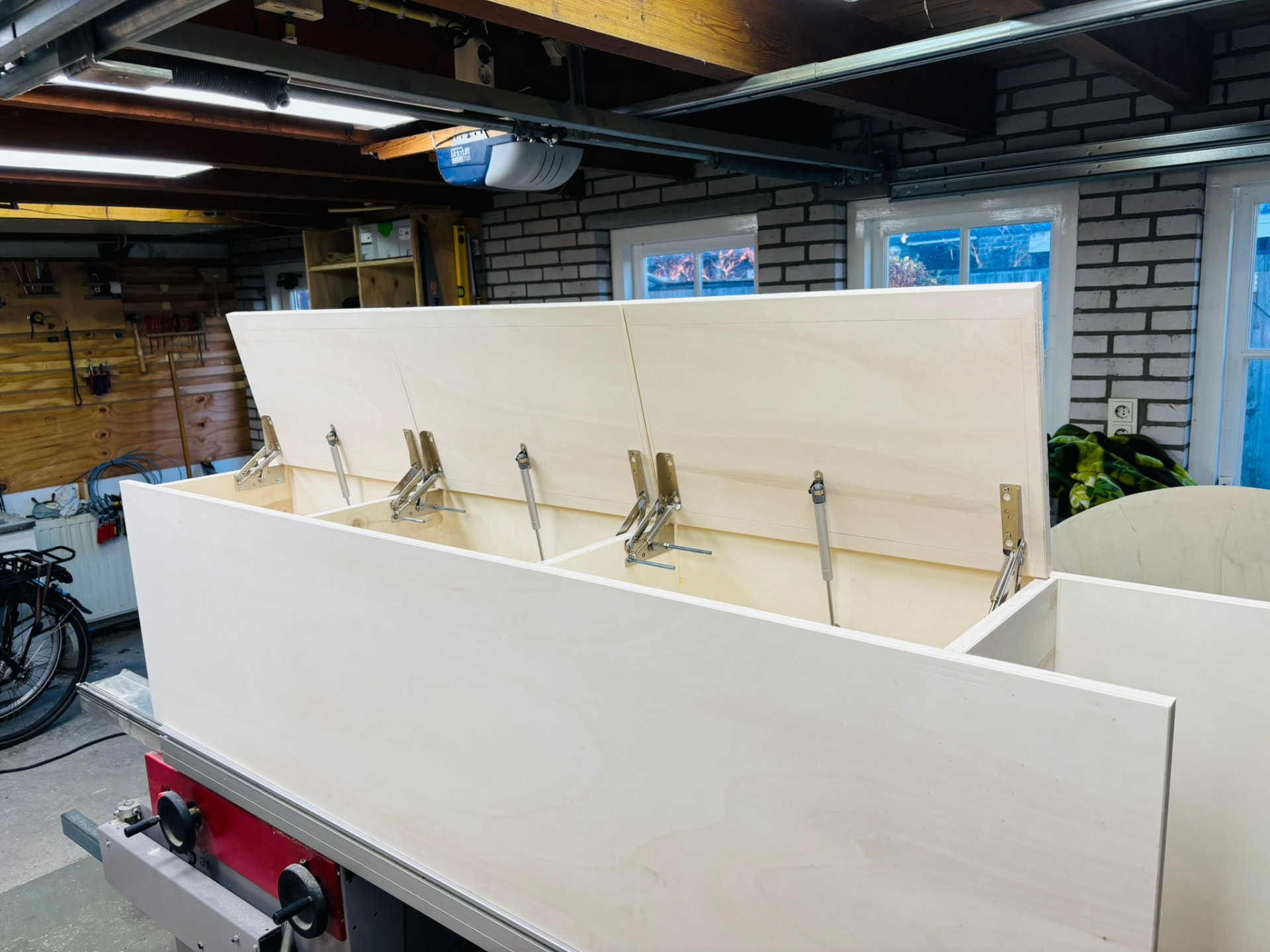 Drie deksels in aanbouw in de werkplaats, opengehouden door gasdrukveren